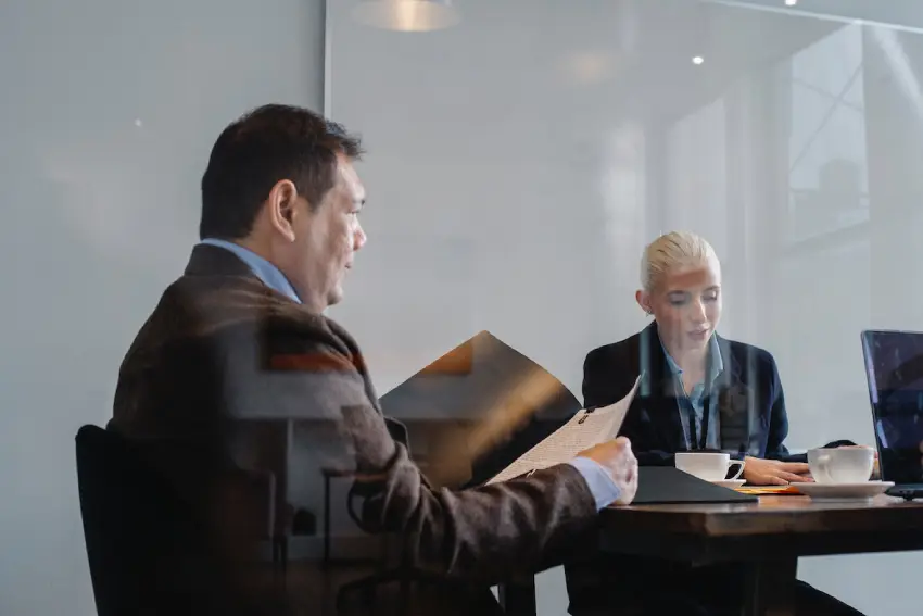 Two people sitting at a table in front of a glass wall.