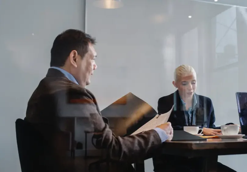 Two people sitting at a table in front of a glass wall.